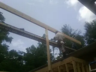 Carpenter setting a ridge beam over a new addition frame — Ice Dam Removal by Roofing Brothers in Center Junction