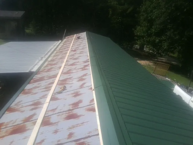 Old rusted panels beside newly installed green metal roofing — Wind Damage Roof Repair by Roofing Brothers in Center Junction