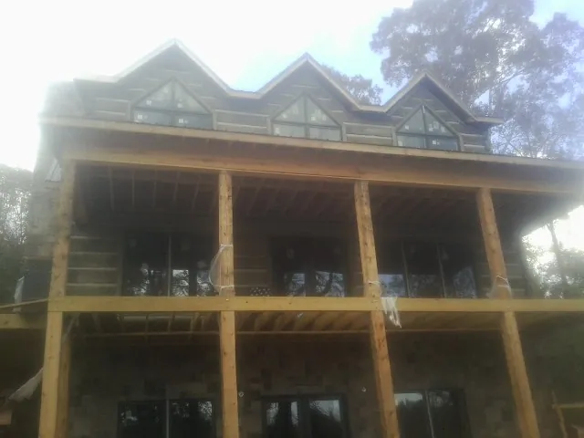 Dormers and porch framing on a large log home under construction — Roof Coating work by our crew in Center Junction