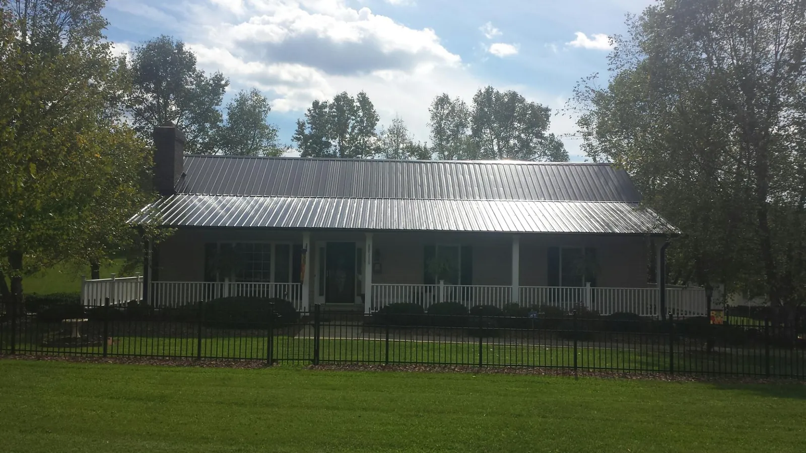 Gray metal roof on a brick ranch with a full width front porch — Gutter Guard Installation work by our crew in Center Junction