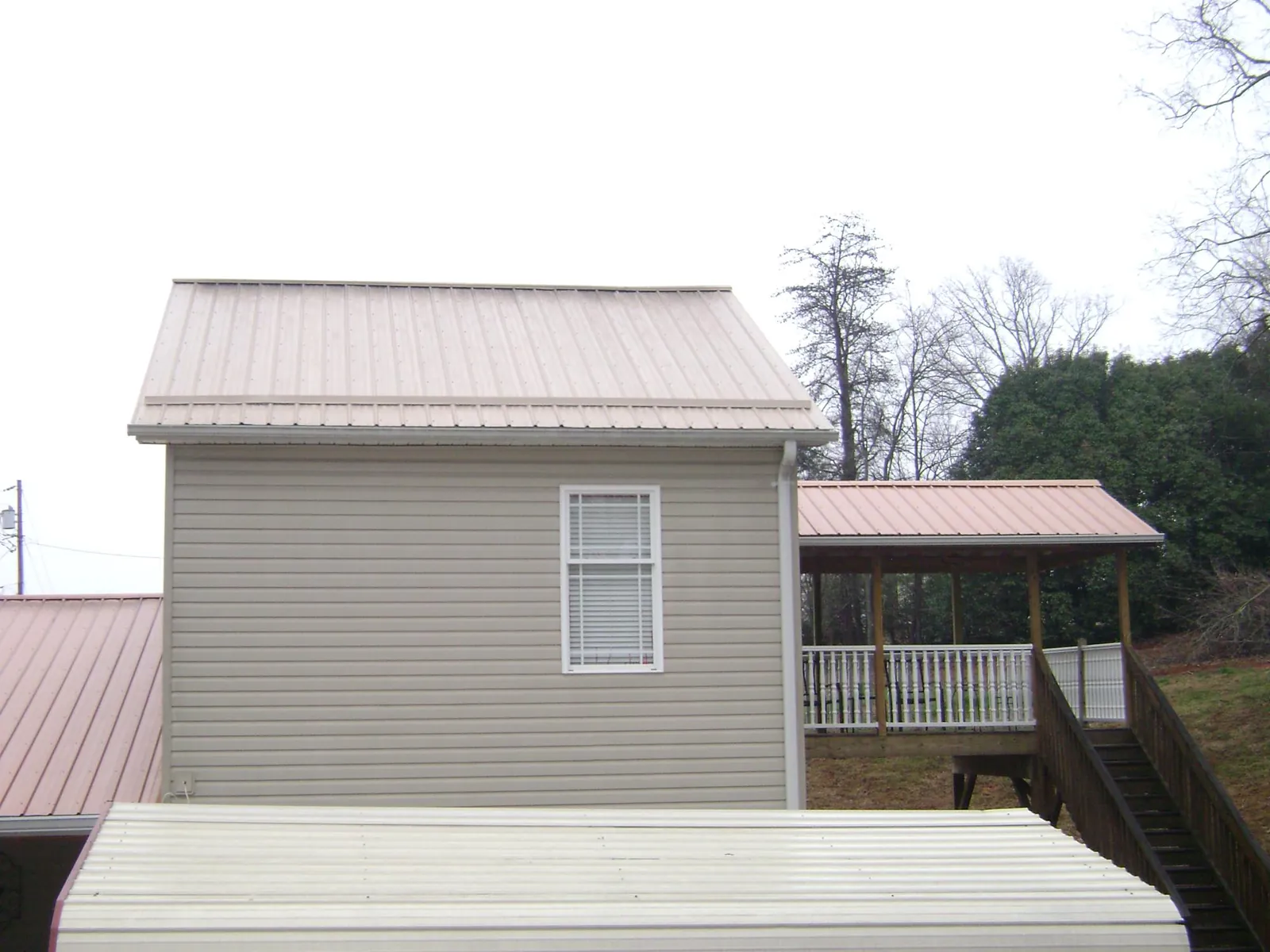 Tan metal roofs on a two story addition and attached porch, from a Roof Replacement job in Center Junction